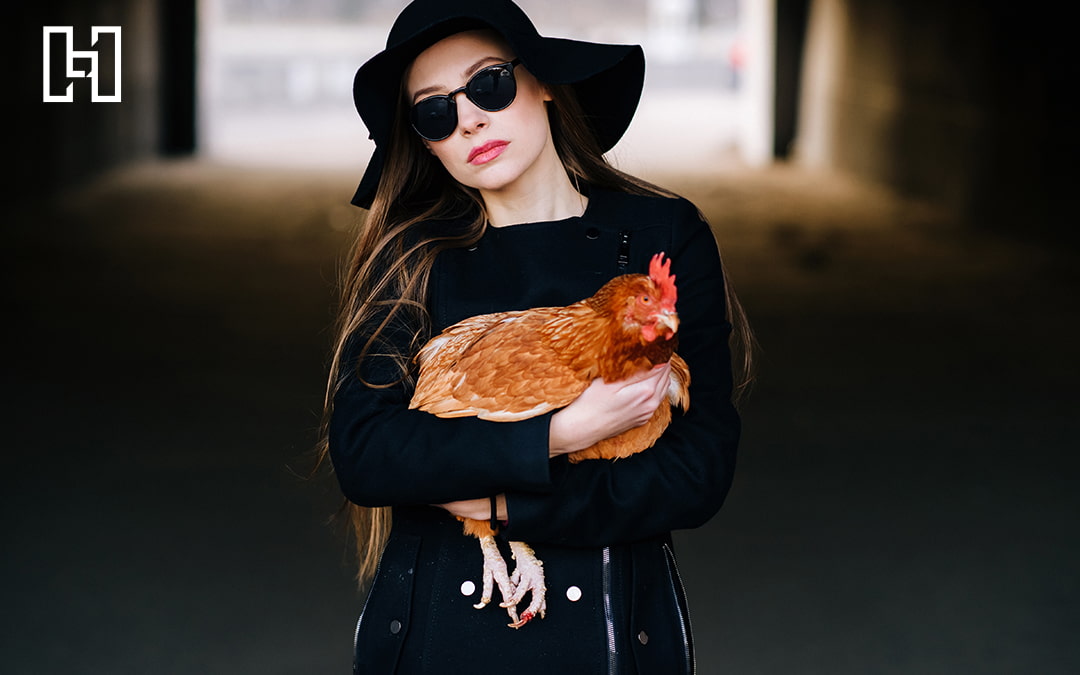 Woman Wearing All Black and Sunglasses Holding a Rooster