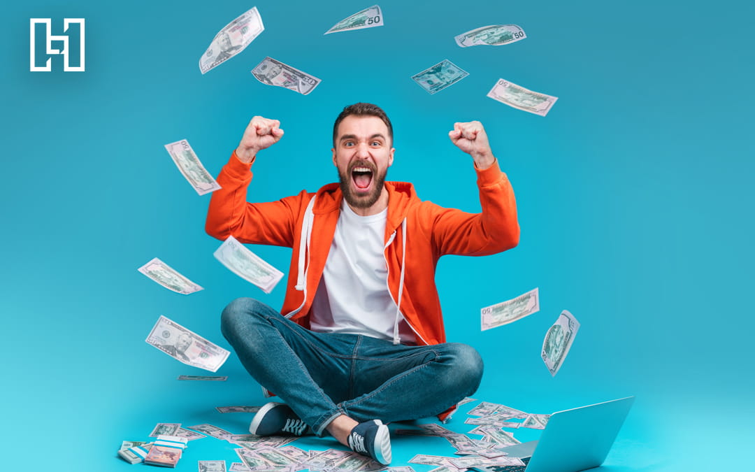 Man sitting down with hands up in celebration while money rains down