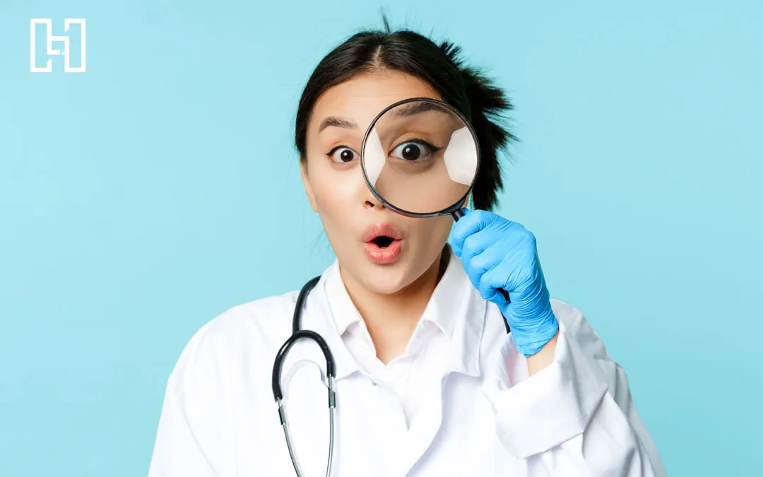 Female doctor in white coat, stethoscope, and rubber gloves holding up a magnifying glass to her eye for medical SEO