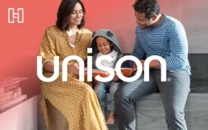 Woman, man, and child sitting together reading a picture book with Hurrdat and Unison logos in front