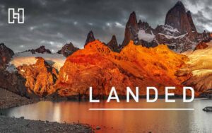 Landscape of mountains lit up by sunset beside water for LANDED Travel marketing case study