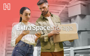 Couple looking at tablet while carrying moving box and standing in storage unit with Extra Space Storage and Hurrdat logos in foreground
