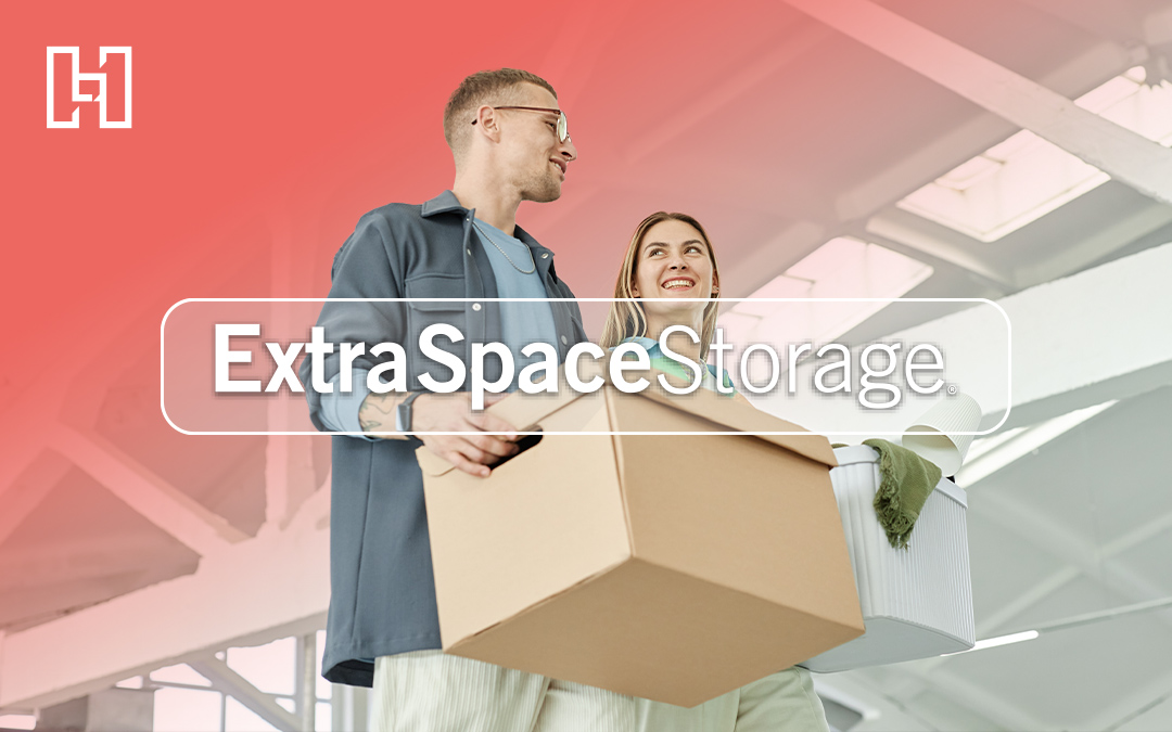 Two people carrying storage bins and boxes in a modern warehouse-style space